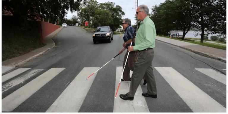 Men with canes crossing at a cross walk.
