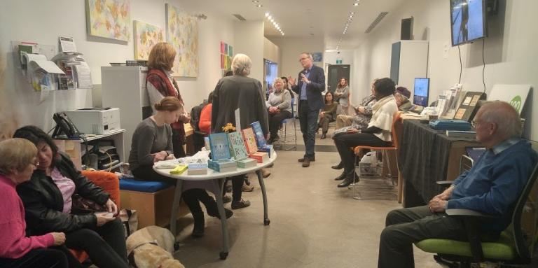 Photo of a Book Launch event with Terry Fallis speaking with group of CNIB participants.