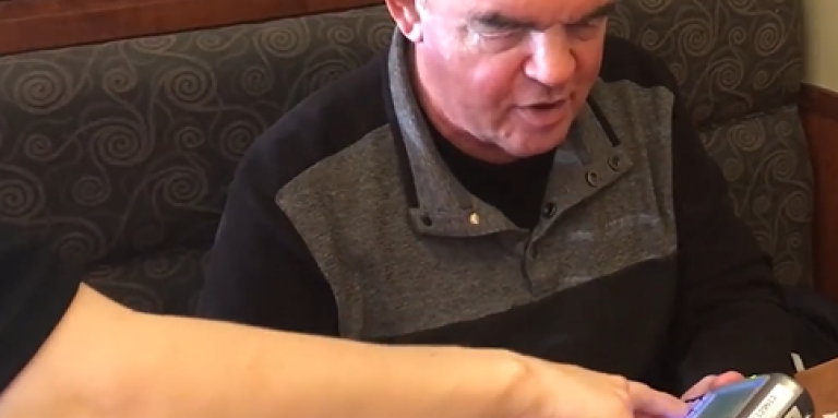 A server helps a man use an inaccessible point of sale terminal at a restaurant. 