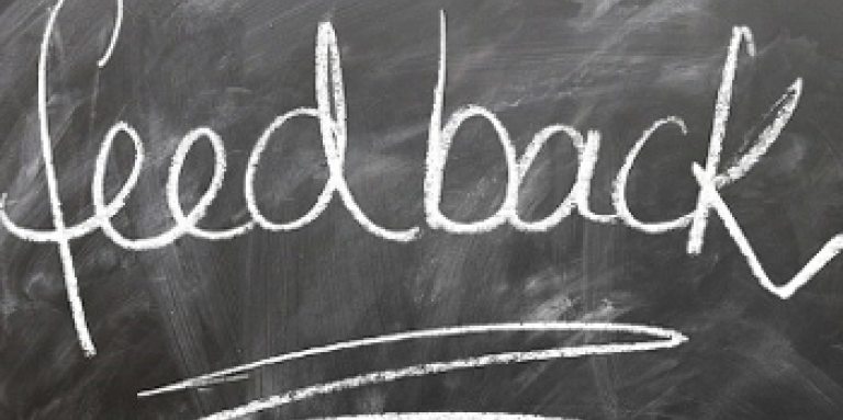 A dirty chalkboard with white text written in chalk on it. Text "Feedback." 