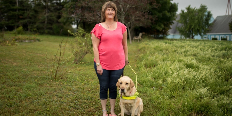 Shawny Ross standing outside with her guide dog Callie, smiling for the camera.