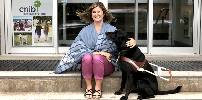 Shelley Adams and her guide dog Pogo, sitting on the steps of CNIB Halifax.