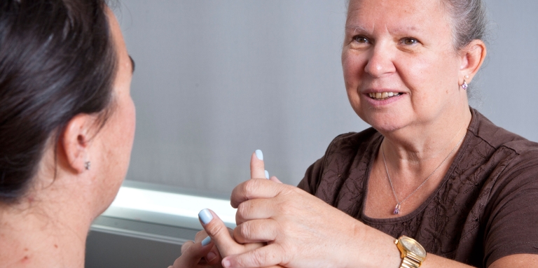 a woman touches another woman's hand reading a symbol