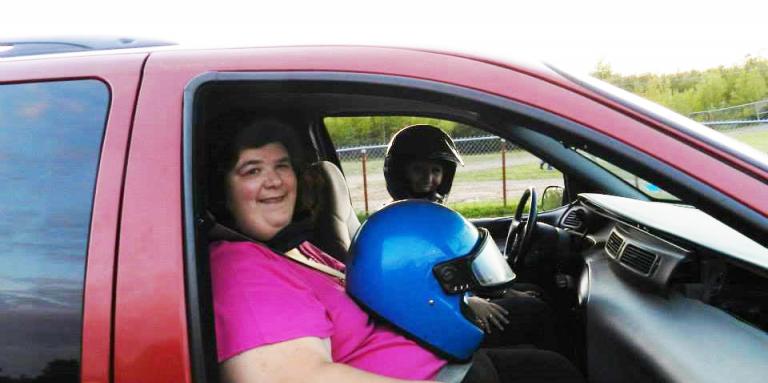 Julie Morneault sitting in a red truck with a blue motorcycle helmet on her lap.