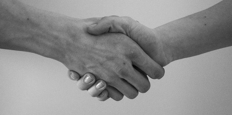 Photo en noir et blanc d'un gros plan sur les mains de personnes qui se serrent la main.
