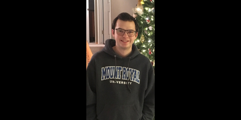 A photograph of Mark wearing a Mount Royal University hoodie.