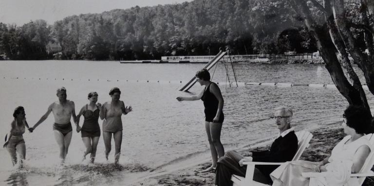 An old black and white photograph of people at CNIB Lake Joe running into the lake.