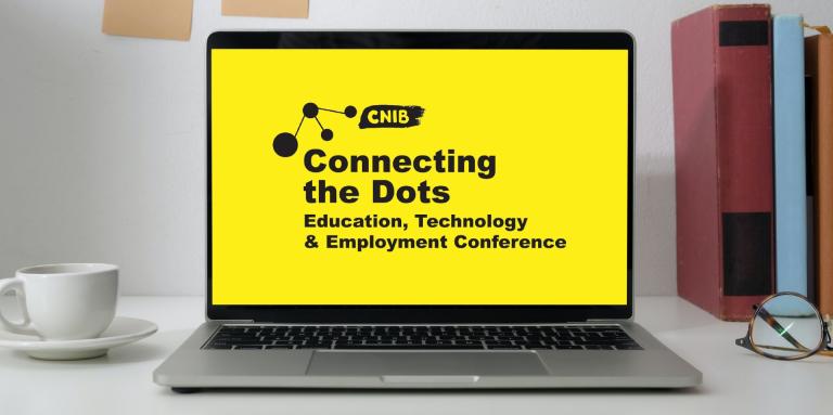 A laptop computer sits on a home-office desk. Displayed on the screen is the Connecting the Dots logo.