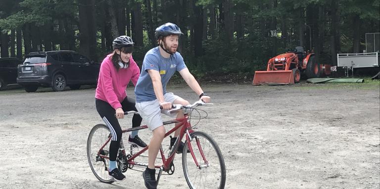 Two young adults tandem cycle at CNIB Lake Joe.