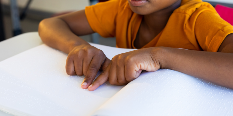 A young child reads a braille book. 