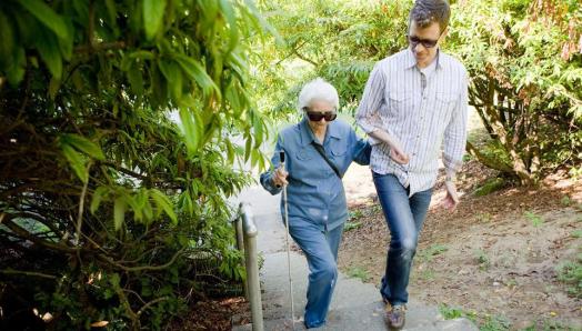 sighted guide walking with a woman using a white cane