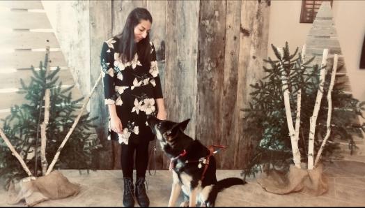 Stela Trudeau and her German Shepherd guide dog exchanging a look at one another, in front of a Christmas-themed photo backdrop.