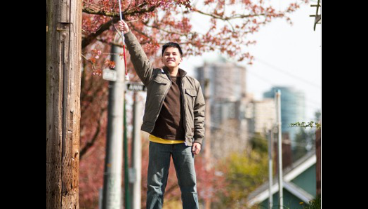 A young man raising proudly his white cane in the air.