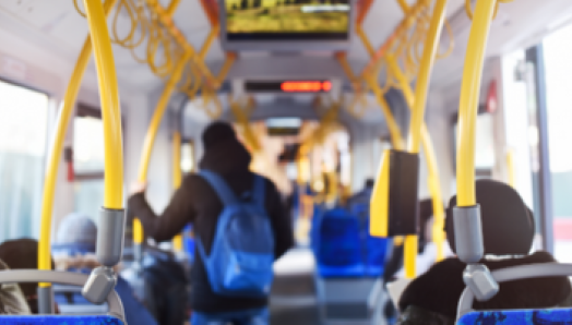Intérieur d’un autobus urbain. Les usagers sont assis et debout à l’intérieur de l’autobus.