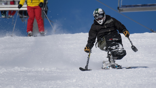 A para-alpine skier zooms down a snowy slope.