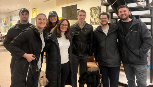 A group photo of Larissa and Shannon with four production crew members from the Ontario Police video and Jack, a handler featured in the video, at the GTA Community Hub. Larissa and Jack are accompanied by their guide dogs.