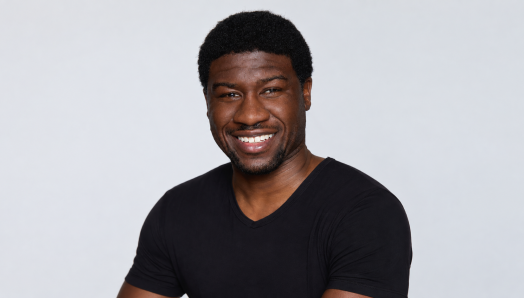 Ben Akuoko, a man with dark skin wearing a black t-shirt, smiles for the camera